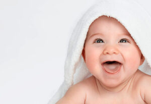 baby smiling lying under a towel